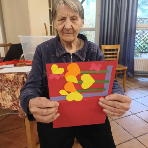 Seniorka prezentująca otrzymaną kartkę z życzeniami