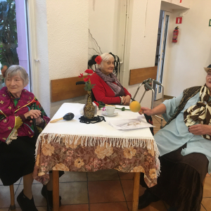 Trzy Seniorki siedzące przy stole w kostiumach stylizowanych na hiszpanki.