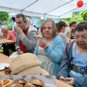 Seniorzy podczas posiłku przy zastawionych piknikowych stołach 