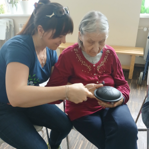 Seniorka z terapeutką podczas gry na instrumencie.