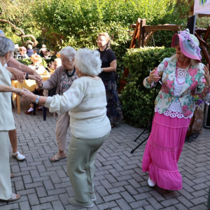 Cztery osoby tańczące w ogrodzie.