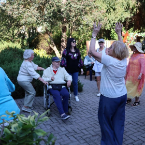 Grupka Seniorów tańcząca w ogrodzie.