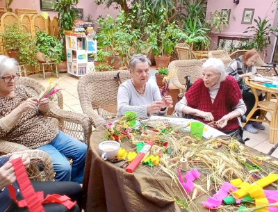 Panie przy stole robią palmy wielkanocne