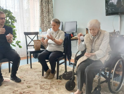 Trener pokazuje Mieszkankom ćwiczenie z piłką