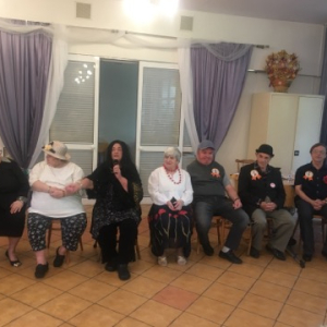 Grupa seniorów siedząca w rzędzie na krzesłach
