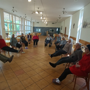 Seniorzy zgromadzeni w okręgu podczas ćwiczeń nóg.